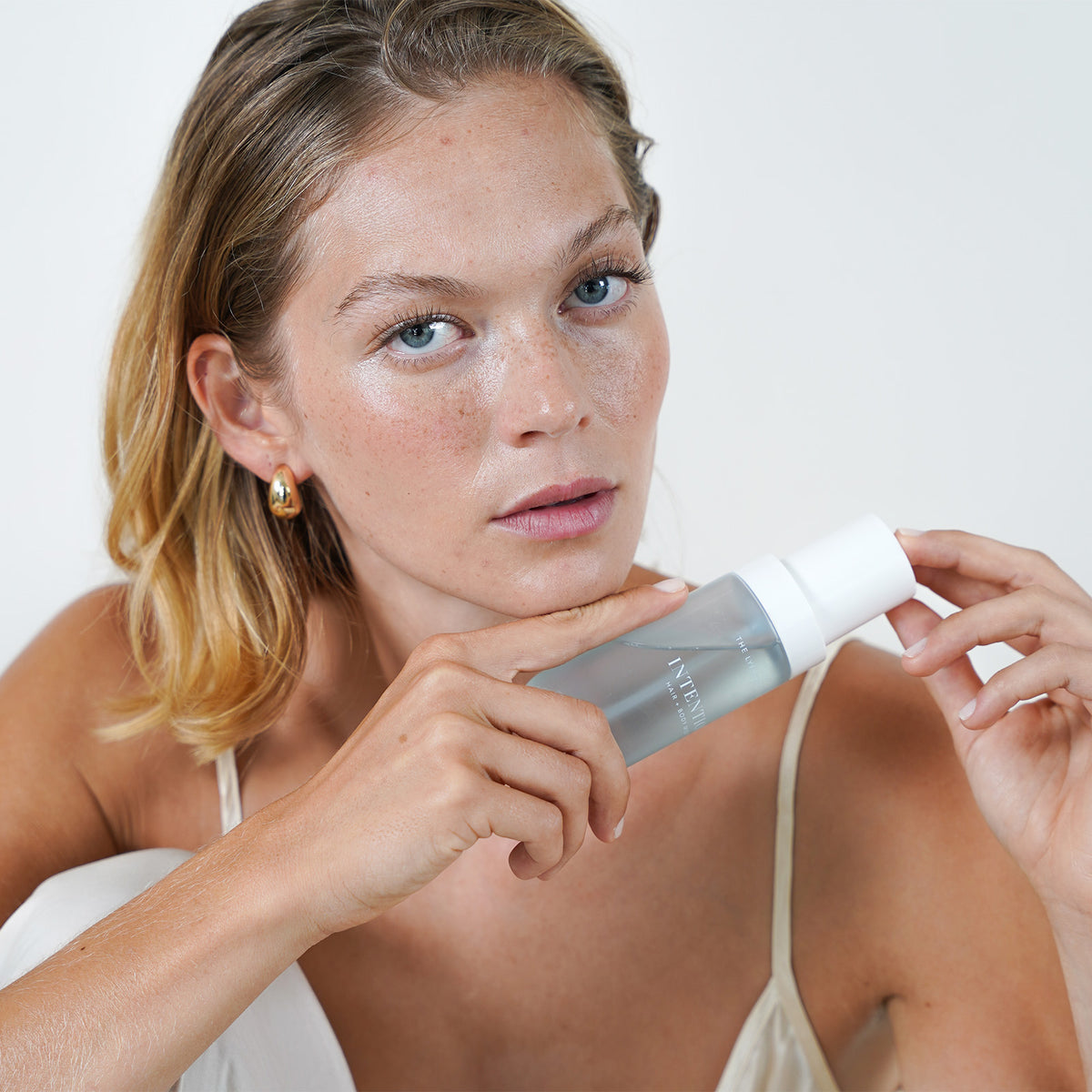 Model holding The Lyfestyle Co. Intention Hair & Body Mist beneath her chin.