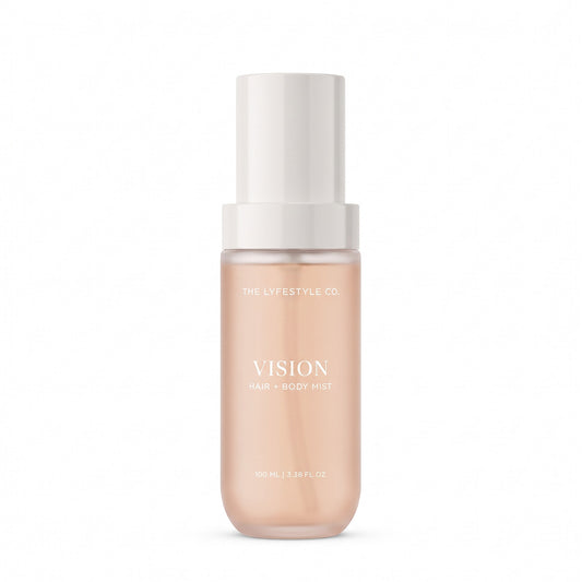 A bottle of The Lyfestyle Co. Vision Hair & Body Mist, featuring a frosted plastic bottle filled with a light pink liquid and a white spray dispenser, set against a plain white background.